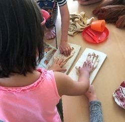 Ein Kind vergleicht seine Hand mit dem Handabdruck eines Orang-Utans.
