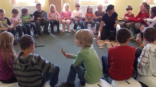 Children sit in a circle at an environmental education event.