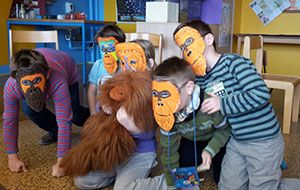 Eine Gruppe Schulkinder mit selbstgebastelten Orang-Utan-Masken und unserem Orang-Utan-Maskottchen Ginting, einer Handpuppe.