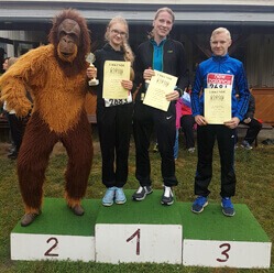 Unser Orang-Utan-Maskottchen steht zusammen mit 3 Teilnehmern des Spendenlaufes auf einem Siegertreppchen.