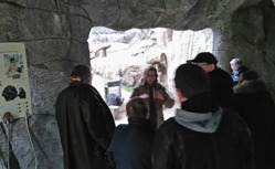 Eine Gruppe Menschen sammelt sich um einen Redner im Affenhaus.