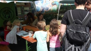 Einige junge Besucher stehen an unserem Stand und basteln sich Orang-Utan-Masken.