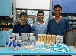 Die drei Tierärzte Dr. Popowati, Dr. Ketut und Dr. Prima stehem freudig lächelnd hinter dem Tisch mit den gespendeten Medikamenten.