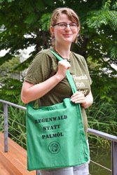 Susann Jänig mit einem neuen grünen Stoffbeutel über der Schulter. Auf dem Beutel steht „Regenwald statt Palmöl“.