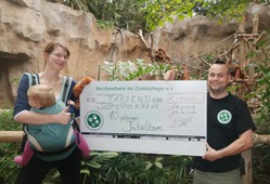 Tierpfleger Robert Eisenberg überreicht Susan Jänig einen großen Spendenscheck im Zoo Leipzig.