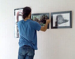 Ein Mann hängt einige Bilder an eine Wand.