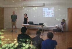 Markus Menke und Stefanie Henkel bei ihrem Pilotprojekt in einem großen Klassenraum mit einer PowerPoint-Präsentation und einigen Zuschauern.