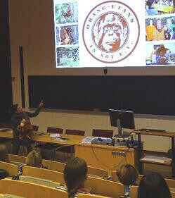 Ein Hörsaal mit einer an die Wand projizierten Präsentation. Das Publikum besteht aus Kindern.