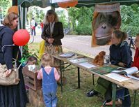 Orang-Utans in Not e.V.-Infostand bei der Ökofete Leipzig. Eine Mutter mit Kind steht am Stand und schaut ihrer kleinen Tochter beim Stochern am Stocherkasten zu.