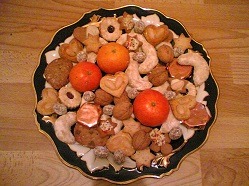 Ein Teller mit weihnachtlichen Leckereien (Mandarinen, Lebkuchen, Plätzchen).