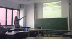 Eine Umweltbildnerin zeigt auf eine Präsentation an der Wand eines Klassenraums.