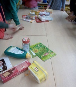 Kinder sortieren Lebensmittelverpackungen auf einem Tisch (Schokocreme, Kekse, Margarine).