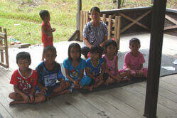 Auf dem Bild sitzen sechs Kinder in einer Reihe auf der Veranda des Umweltbildungszentrums.
