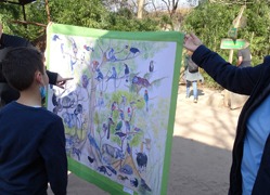 Kinder stehen vor einem großen Plakat, auf dem Tiere des Regenwaldes abgebildet sind.