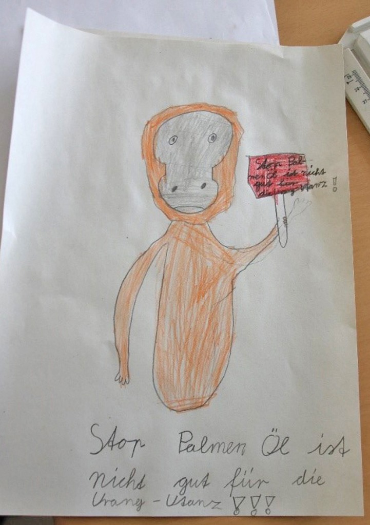 Die Schüler gestalteten Bilder zum Thema Regenwaldzerstörung. Ein Orang-Utan hält ein Schild hoch mit dem Text: „Stop. Palmenöl ist nicht gut für die Orang-Utans!!!“