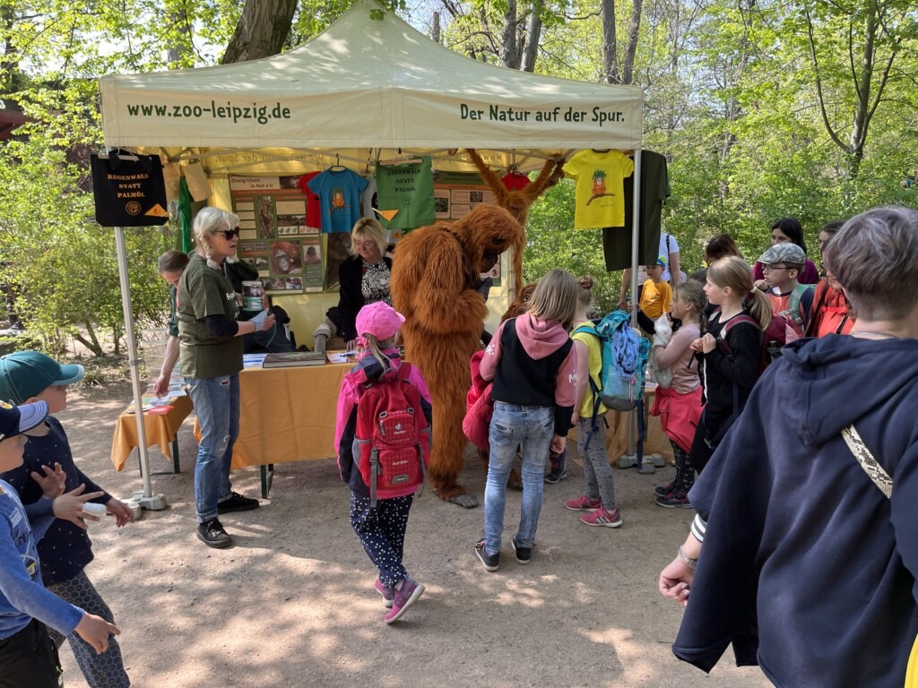 Am Infostand des Vereins steht eine Person im Orang-Utan-Kostüm und unterhält sich mit Besuchern.