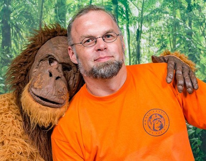 Portrait von Sebastian Schorr. Ein Mensch im Orang-Utan-Kostüm umarmt ihn.