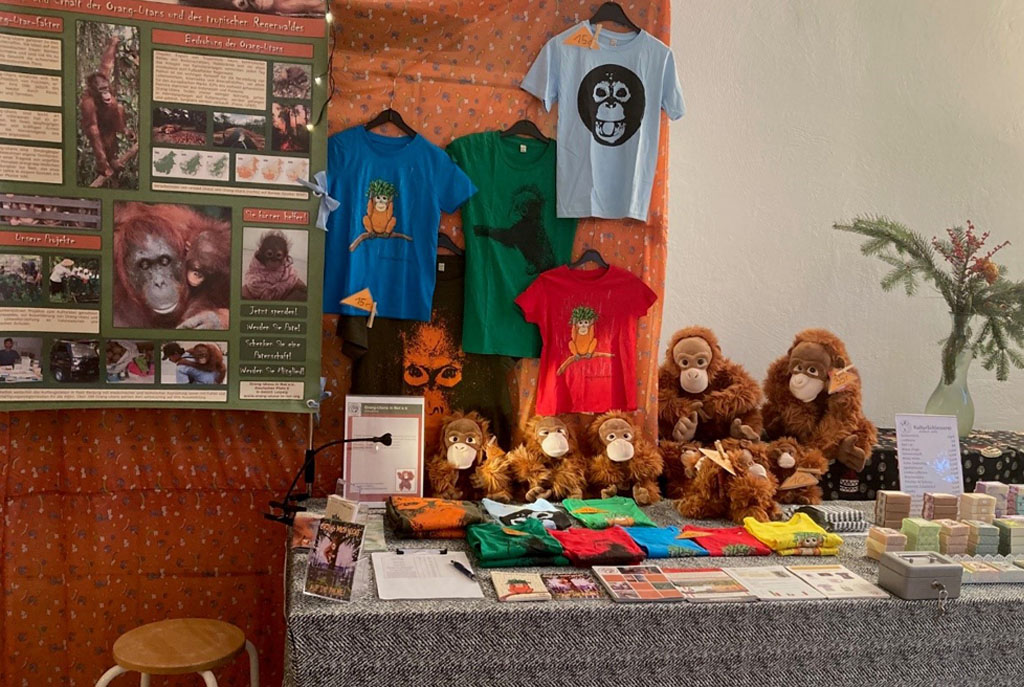 Informationsstand mit T-Shirts und Orang-Utan-Plüschtieren.