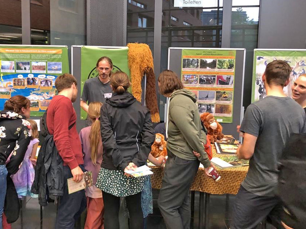 Ein Mitarbeiter des Vereins spricht zu interessierten Besuchern, die vor unserem Informationsstand stehen.
