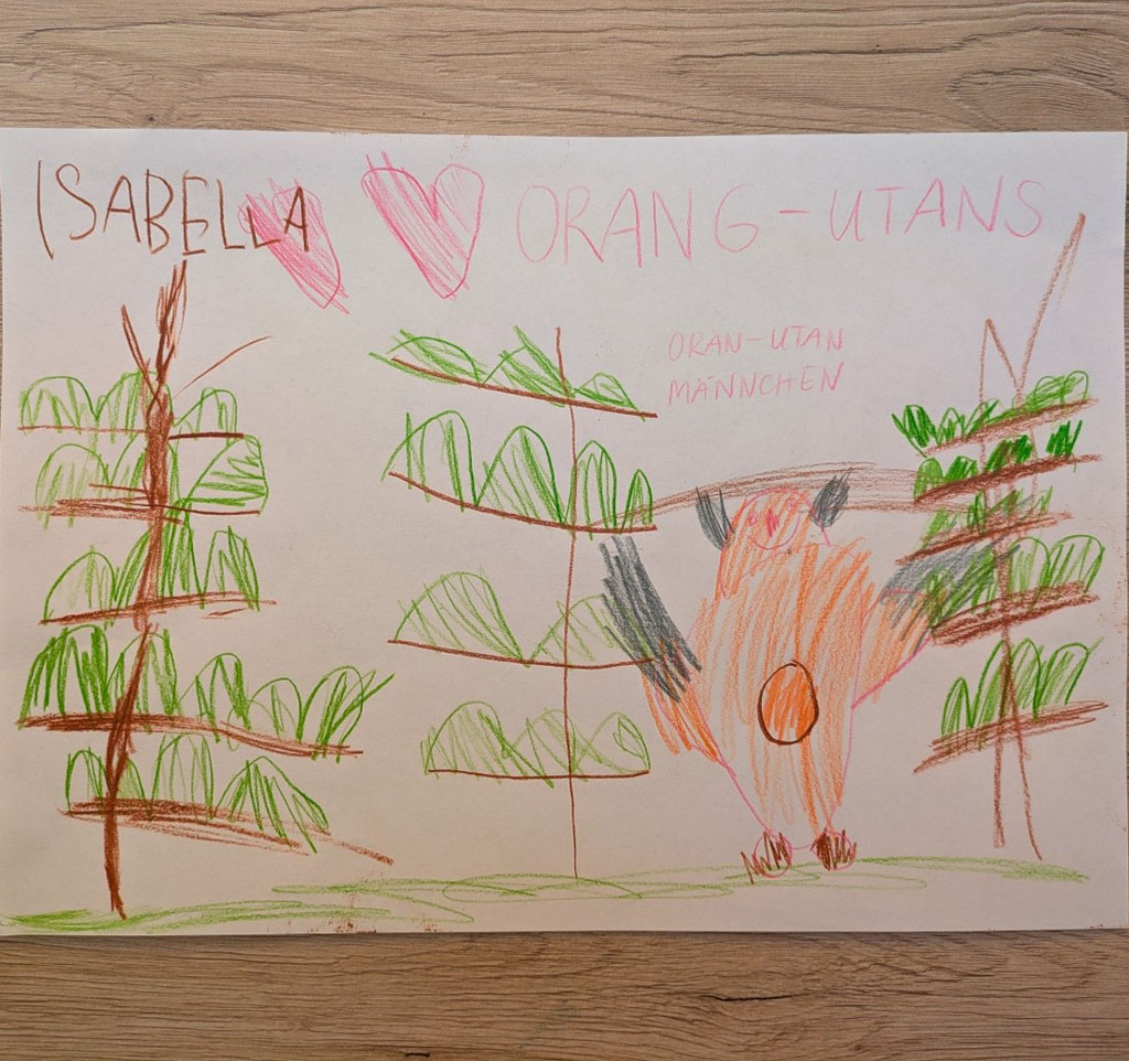 Eine Kinderzeichnung mit drei Bäumen, einem Orang-Utan-Männchen. Und einem großen Herzen liegt auf einem Tisch. Gemalt wurde das Bild von Isabella.