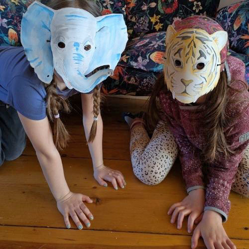 Zwei Kinder mit selbstgebastelten Tiermasken vor dem Gesicht. Ein Kind trägt eine Elefantenmaske und ein Kind eine Tigermaske.
