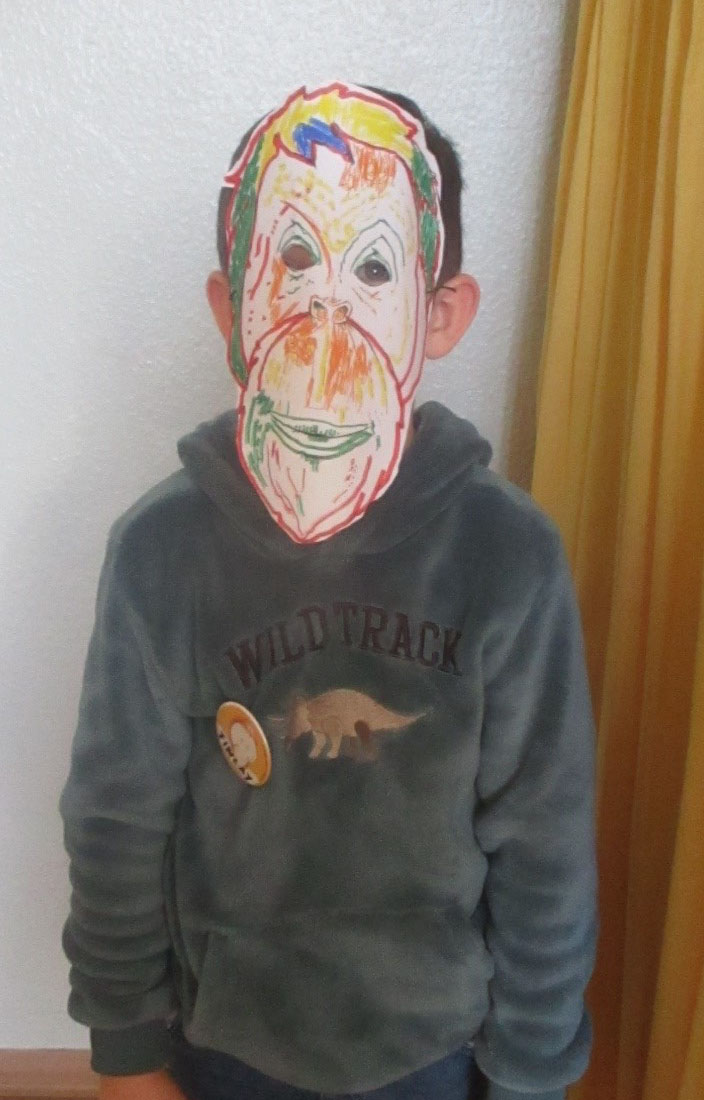 Ein Kind trägt eine bunte Orang-Utan-Maske