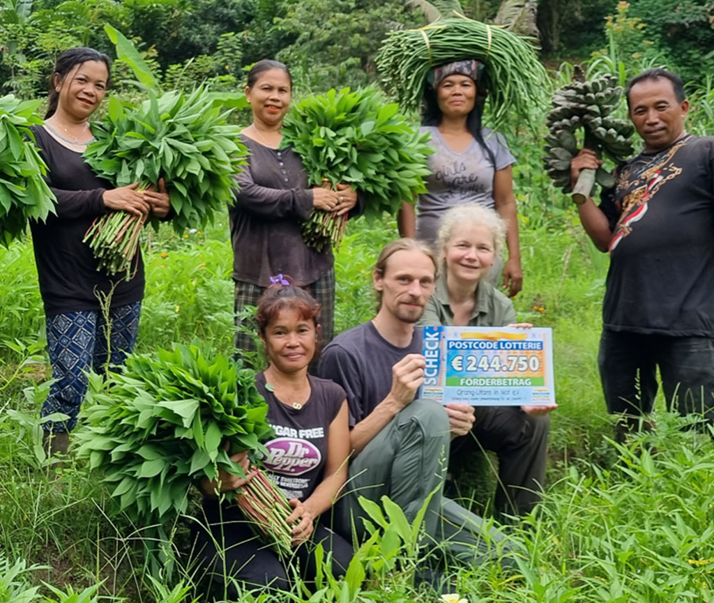 Gruppenfoto mit zwei Mitgliedern des Vereins und Mitarbeitern des Eco-Farming-Teams des Orangutan Haven. Die Vereinsvorsitzende hält den symbolischen Scheck in den Händen. Alle lachen in die Kamera.