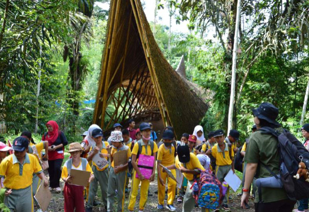Eine Schulklasse steht vor der großen Bambusbrücke im Orangutan Haven.