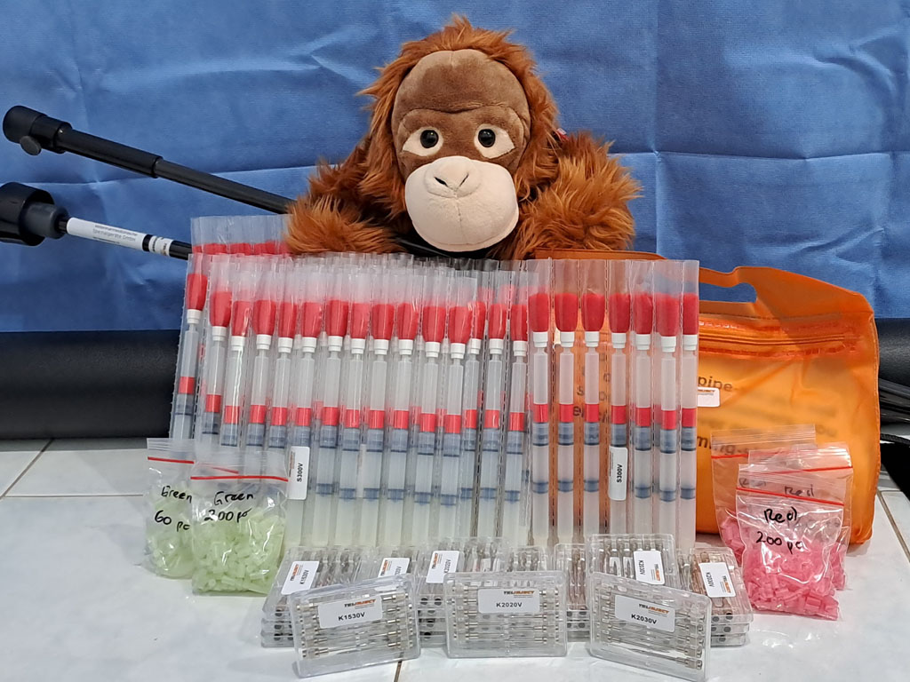 Ein Plüsch-Orang-Utan sitzt hinter hinter diversen Ausdrüstungsteilen für Blasrohre.