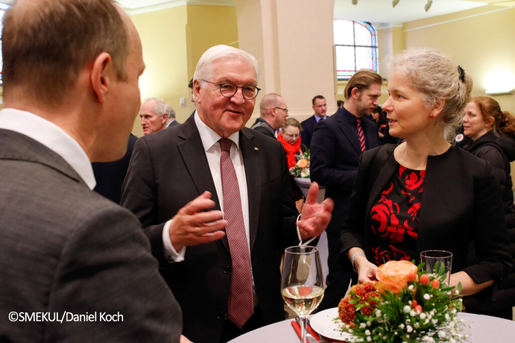 Staatsminister Wolfram Günther, Bundespräsident Frank-Walter Steinmeier und Julia Cissewski unterhalten sich auf dem Empfang.