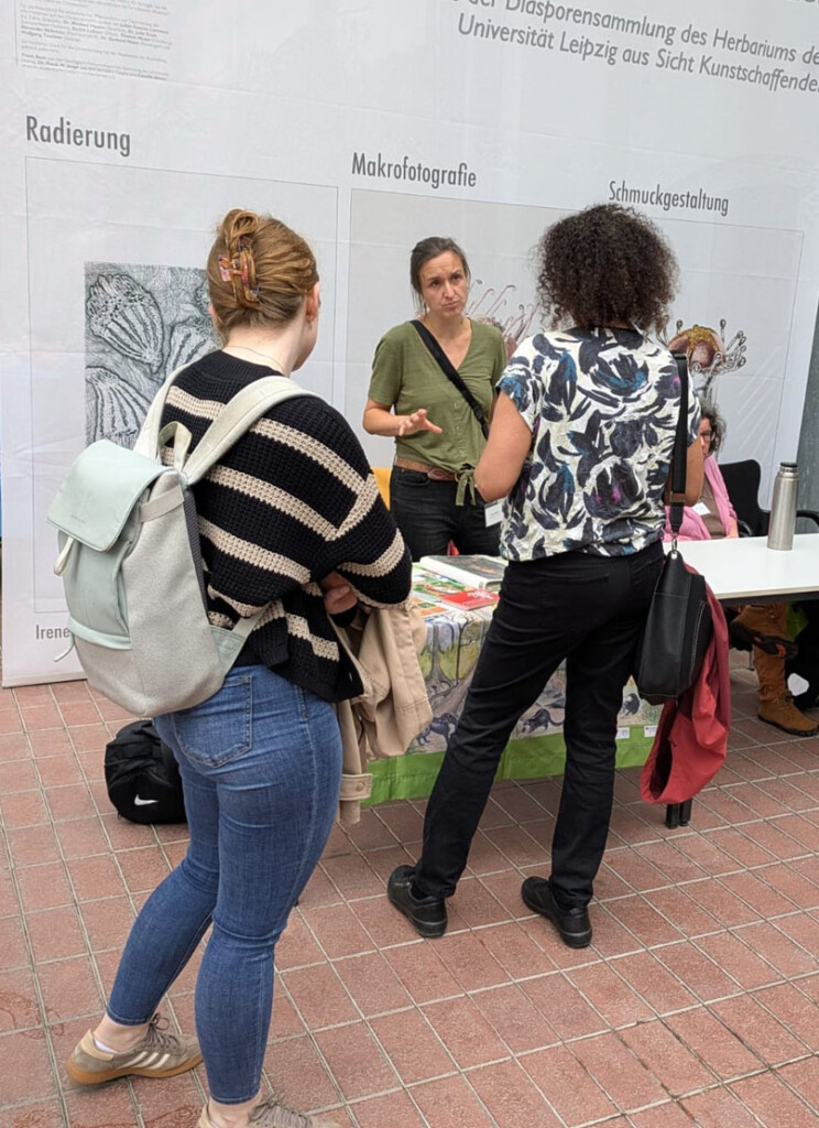 Unsere Umweltbildnerin steht hinter dem Informationsstand und unterhält sich mit Besuchern.